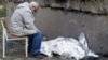 Дедушка сидит рядом с накрытым телом 9-летней внучки возле поликлиники, в которой находится бомбоубежище. Во время ракетного удара оно было закрыто, и люди не смогли туда попасть. Киев, Украина, 1 июня 2023 года