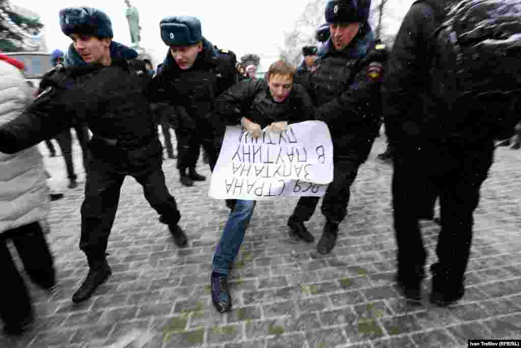 Задержание активиста на Пушкинской площади Москвы. В руках у него плакат "Вся страна запутана в паутину Путина"