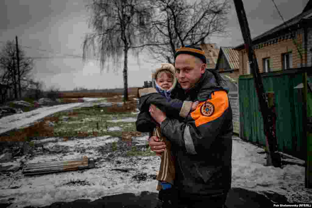Спасатель МЧС выносит ребенка из дома 