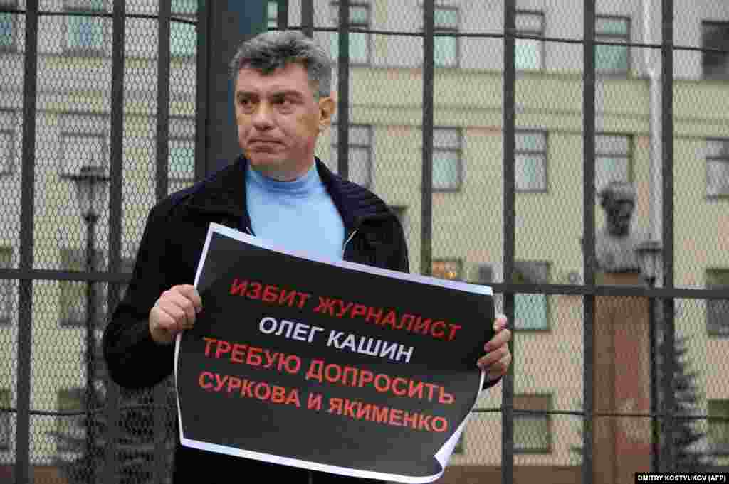 Борис Немцов держит плакат с требованием начать расследование по делу избиения оппозиционного журналиста Олега Кашина 