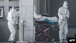 Медики в защитных костюмах и пациент в больнице города Ухань 18 января 2020 года. Фото: STR/AFP
