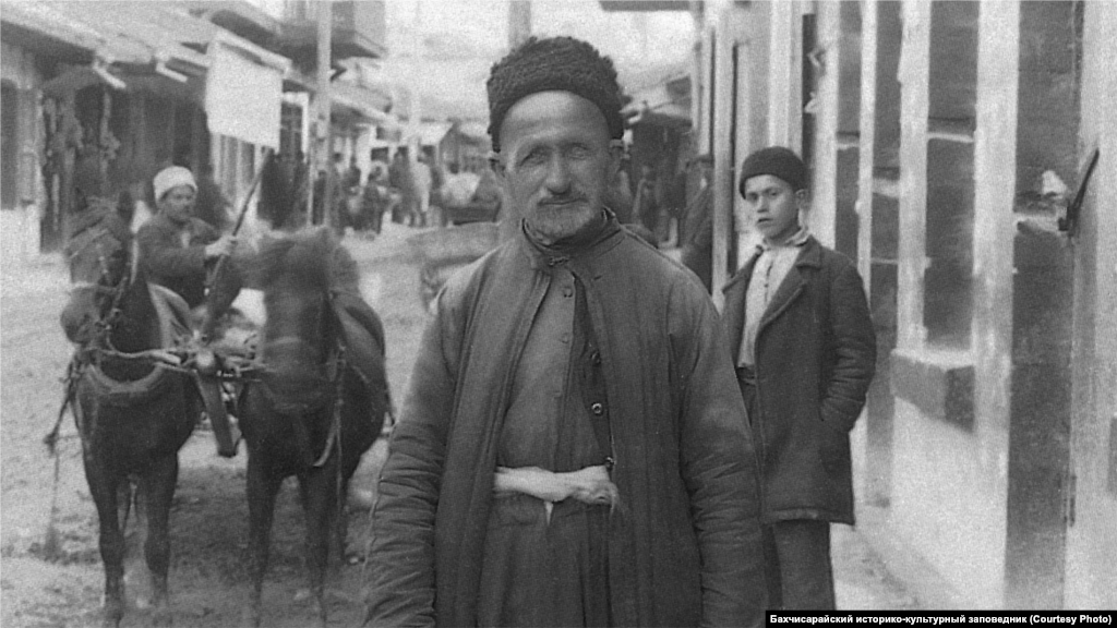 Житель Бахчисарая, 1920-е Мужчины покрывали голову низкой барашковой шапкой, тюбетейкой или феской. Рубаха с широкими рукавами заправлялась в широкие суконные шаровары и подпоясывалась широким кушаком. Поверх рубахи надевали короткий жилет с пуговицами, а сверху – длинный кафтан