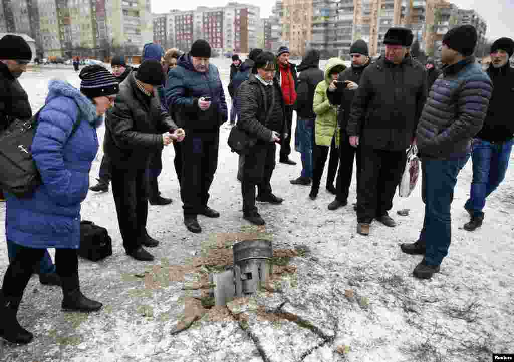 Люди осматривают реактивный снаряд, упавший на одной из улиц Краматорска  