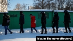RUSSIA - Law enforcement officers walk behind people near a court building during a hearing to consider the case of Russian opposition leader Alexei Navalny, who is accused of flouting the terms of a suspended sentence for embezzlement, in Moscow, Russia